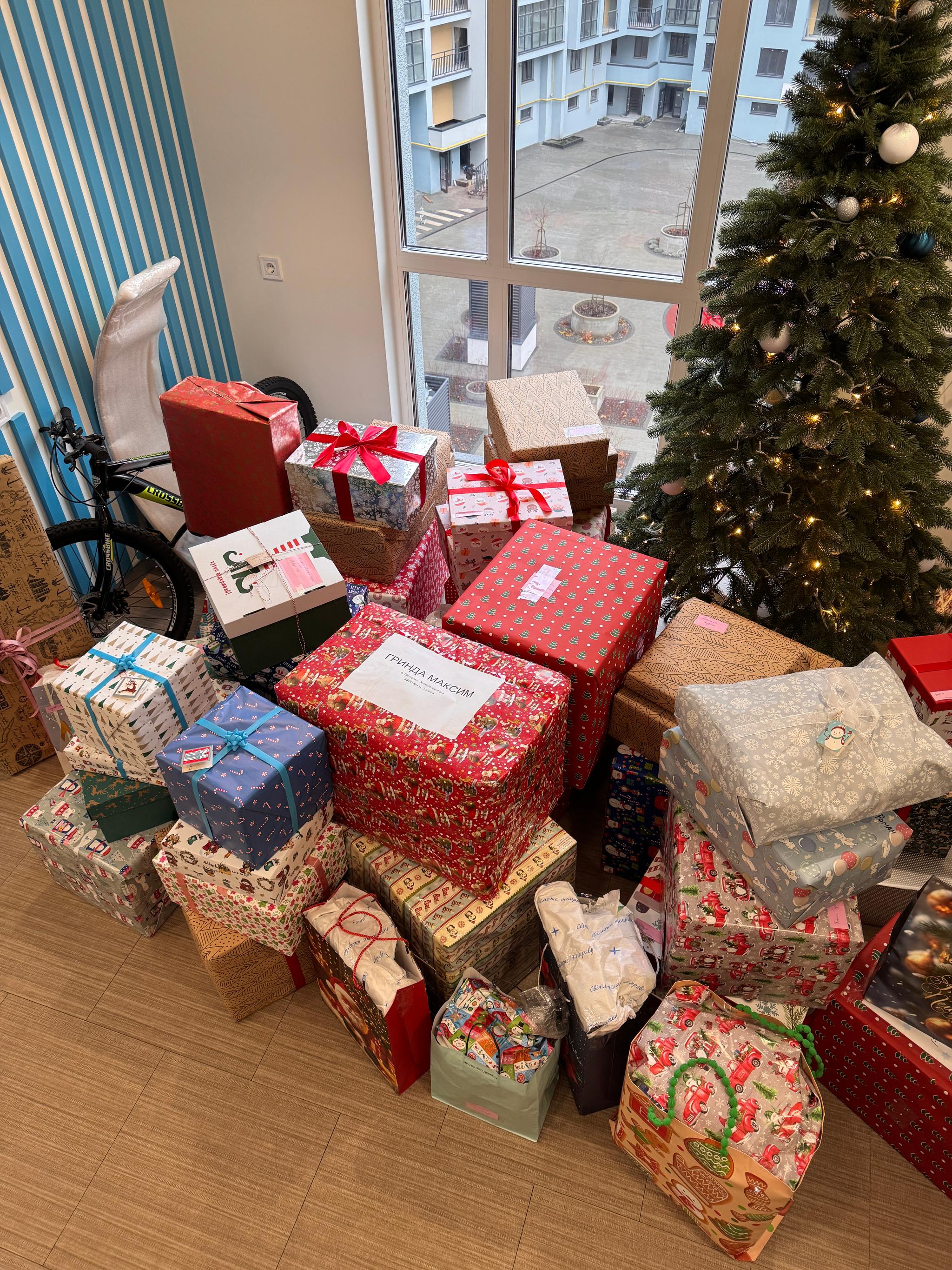 Wrapped Christmas gifts collected by the Binariks team under an office tree